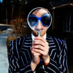 Man in a striped suit looking through a magnifying glass