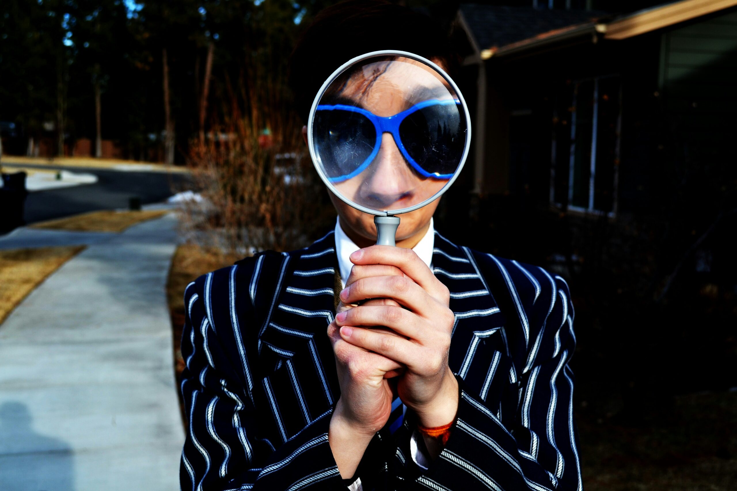 Man in a striped suit looking through a magnifying glass